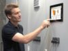 Man operates control PersonalTouch visio on digital display on an electronic control cabinet to operate the wood heating system.